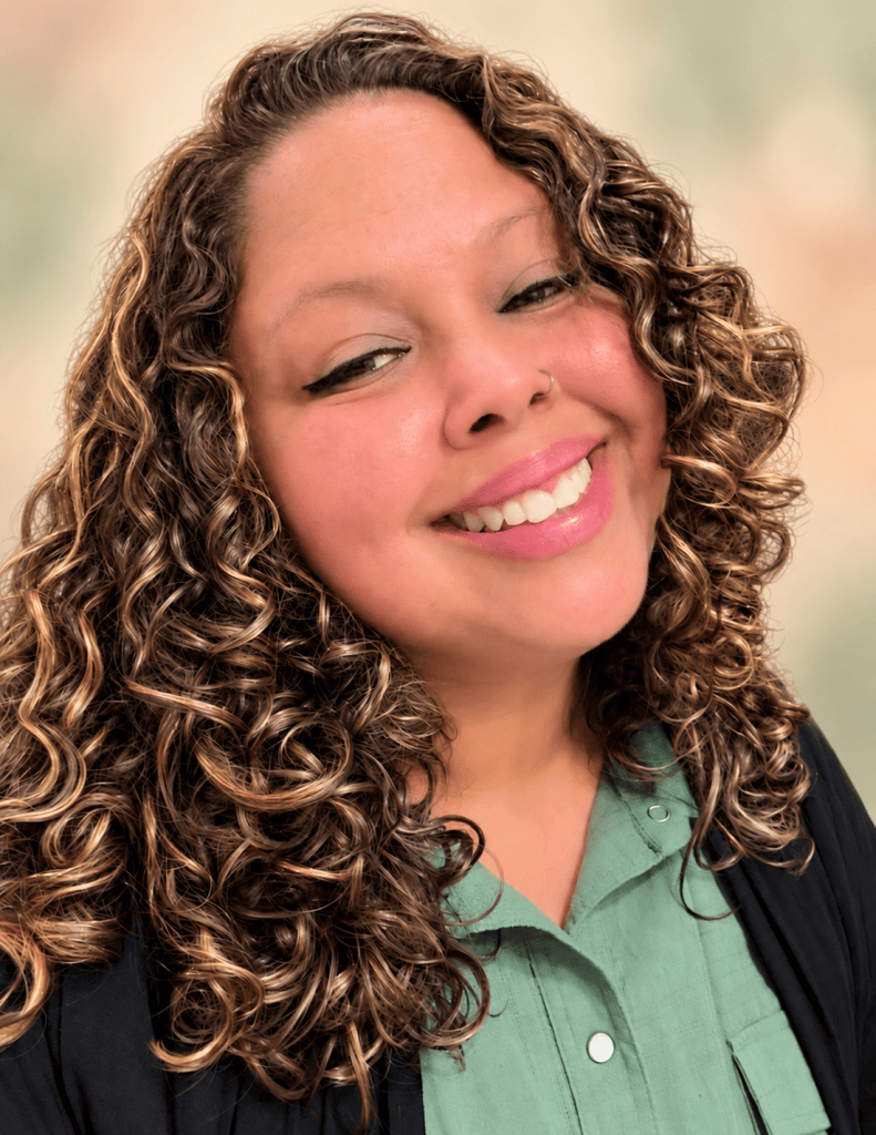Vanessa Chica smiling in a warm portrait with a cream, sage, and peach background